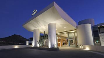 Una entrada de hotel moderna con techo plano y amplias columnas.