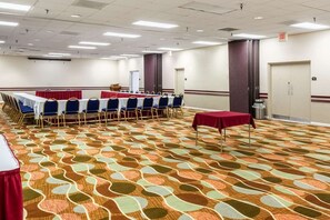 A conference room with a patterned carpet, rows of tables with chairs, and an exit sign. - Best Western Premier Lakeland North (Lakeland)