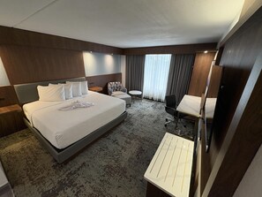 Une chambre d’hôtel avec un grand lit, un bureau, une chaise et un téléviseur.