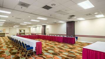 A conference room with a long table, chairs, and a patterned carpet.