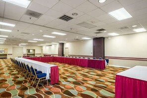 Une salle de conférence avec une longue table, des chaises et un tapis à motifs.