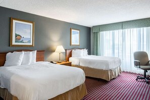 Une chambre d’hôtel avec deux lits, un bureau, une chaise et une fenêtre avec des rideaux.