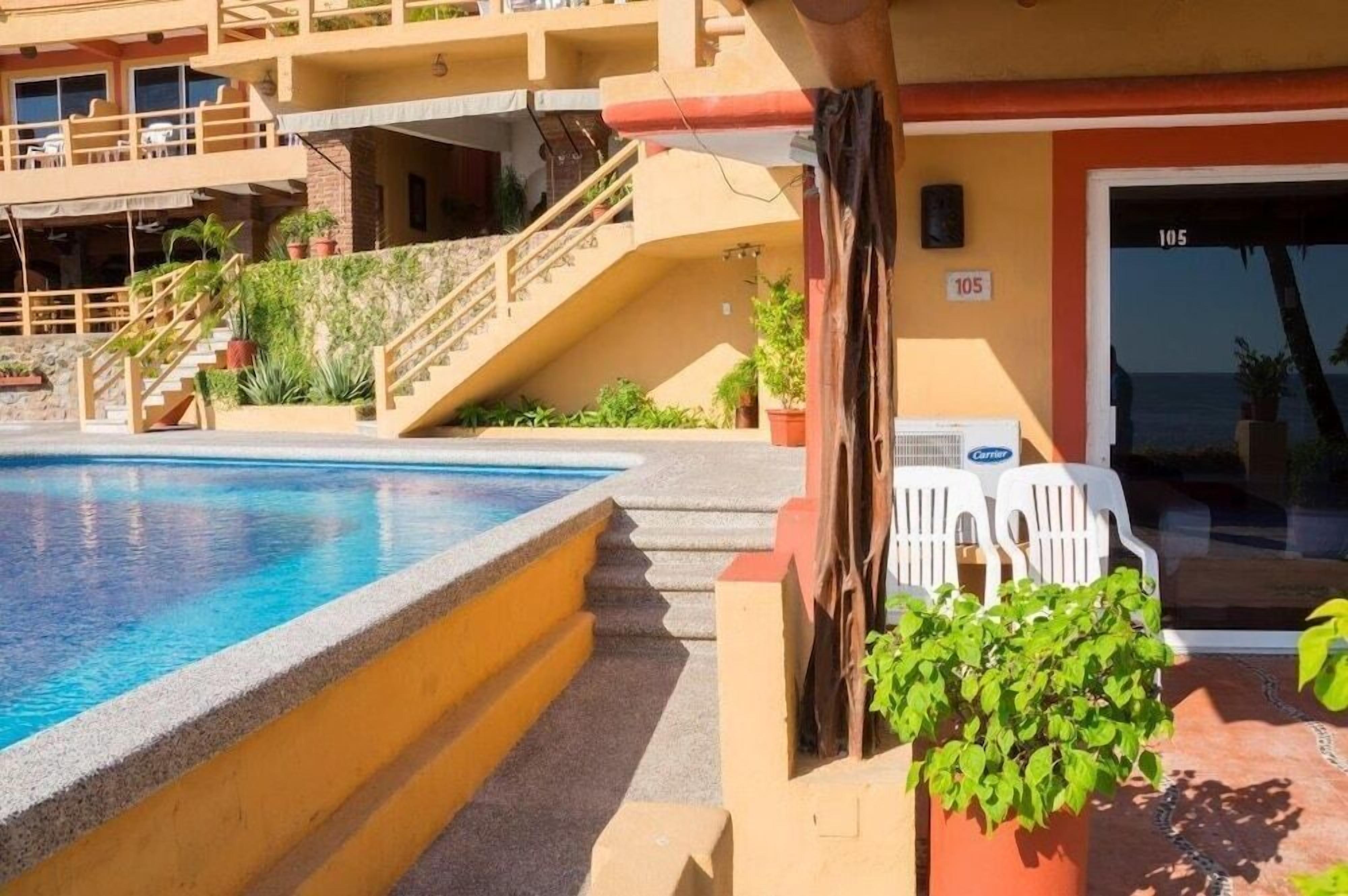 Ein Hotel mit Pool, Außenbereich und einer Treppe zu einer oberen Ebene.