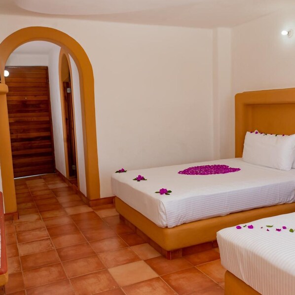 Une chambre d’hôtel avec un lit, un deuxième lit, un escalier en bois et un couloir.