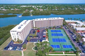 A multi-story hotel with a parking lot, tennis courts, and a marina. - Waterfront Amenities, Walkable Dining & Gulf Beaches Nearby (Indian Shores)