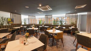 Comedor de hotel con mesas, sillas y vistas al exterior.