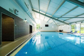 An indoor swimming pool with a clear ceiling, a tiled wall, and a door leading to another room. - Clarion Hotel Newcastle South Boldon EN (Boldon Colliery)