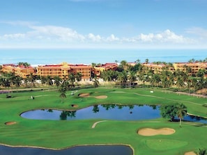 A golf course with bunkers, water hazards, and a hotel with multiple floors and red roofs. - Luxury Suite By Estrella del Mar (Mazatlán)