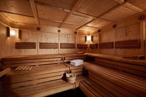 Una sala de sauna con bancos de madera y toallas, una toalla sobre un banco y un cubo.