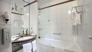 A modern bathroom with a large bathtub, a glass shower enclosure, a vanity with a mirror, and a scale. - Lindner Hotel Leverkusen Bayarena, Part of Jdv by Hyatt (Leverkusen)