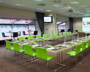 A conference room with a long table, green chairs, a screen, and a projection screen. - Lindner Hotel Leverkusen Bayarena, Part of Jdv by Hyatt (Leverkusen)