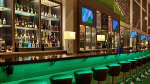 A bar area with shelves of liquor bottles, bar stools, and televisions. - Lindner Hotel Leverkusen Bayarena, Part of Jdv by Hyatt (Leverkusen)