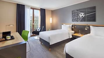 A hotel room with two beds, a desk, a chair, a desk lamp, and a wall art piece.