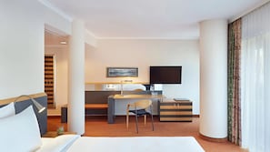 A hotel room with a bed, desk, chair, TV, and a view of the outdoors. - Lindner Hotel Leverkusen Bayarena, Part of Jdv by Hyatt (Leverkusen)