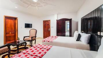 A hotel room with two beds, a television, a chair, and a desk.