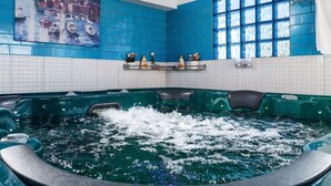 A spa area with a hot tub, blue tiled walls, and a painting of boats. - Hotel Bkbg (Lomé)