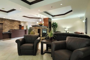A lobby with a stone fireplace, leather sofas, and a reception desk. - Olds Hotel (Olds)