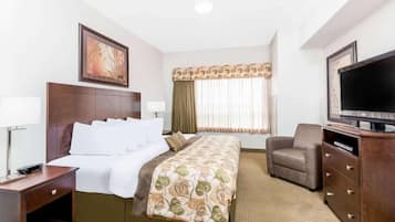 A hotel room with a bed, a TV, a chair, and a desk.