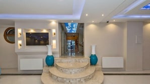 A spacious lobby with a marble staircase, a large TV screen, and a view of the sky through a ceiling opening. - Selenay Hotel Istanbul (Istanbul)