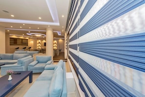 En modern hotellobby med en sittgrupp, en receptionsdisk och en vägg med ett mönster.