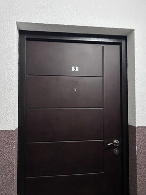 Eine dunkelbraune Tür mit der Nummer 9, einem Schloss und einem Griff.