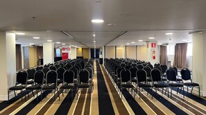 A hotel conference room with rows of chairs, a striped carpet, and a visible exit door. - Hotel Gran Vivenzo Belo Horizonte (Belo Horizonte)