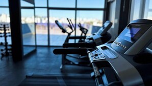 A gym with exercise equipment and a large window offering a view of the city. - Hotel Gran Vivenzo Belo Horizonte (Belo Horizonte)