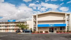 A two-story motel with a blue awning and a sign indicating it's open. - Rodeway Inn Albuquerque NM (Albuquerque)