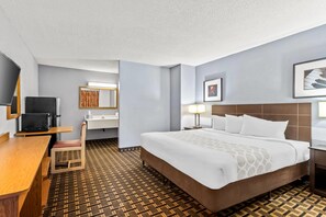 A hotel room with a bed, a desk, a chair, a television, a sink, and a mirror. - Rodeway Inn Albuquerque NM (Albuquerque)