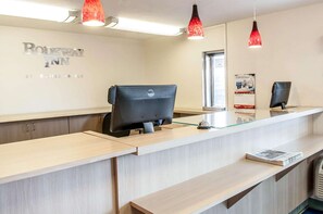 A reception desk with a Dell computer, a glass top, and a sign for Rodeway Inn by Cadice Hotels. - Rodeway Inn Albuquerque NM (Albuquerque)