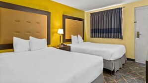 A hotel room with two beds, a nightstand, a lamp, and a window with curtains. - Rodeway Inn Albuquerque NM (Albuquerque)