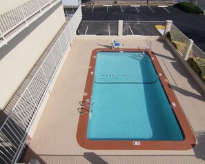A swimming pool with a 5 ft depth marker, surrounded by a white metal fence, on a sunny day. - Rodeway Inn Albuquerque NM (Albuquerque)