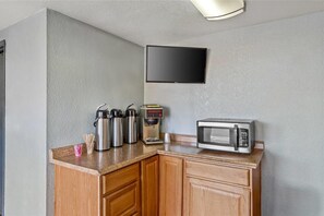 A kitchenette with a coffee maker, a microwave, and stainless steel thermos cups on the counter. - Rodeway Inn Albuquerque NM (Albuquerque)
