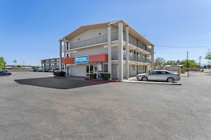 Un hotel de varios pisos con un letrero que dice 'Rodeway Inn & Suites' en un estacionamiento.