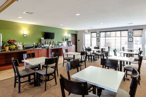 Un restaurante con zona de bufé, varias mesas y sillas, y un televisor.