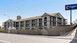 A multi-story Comfort Inn hotel with a central courtyard, a parking lot, and a clear sky. - Comfort Inn Antioch - Century Plaza (Antioch)