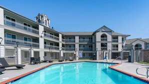 A swimming pool with lounge chairs and a multi-story building with balconies. - Comfort Inn Antioch - Century Plaza (Antioch)