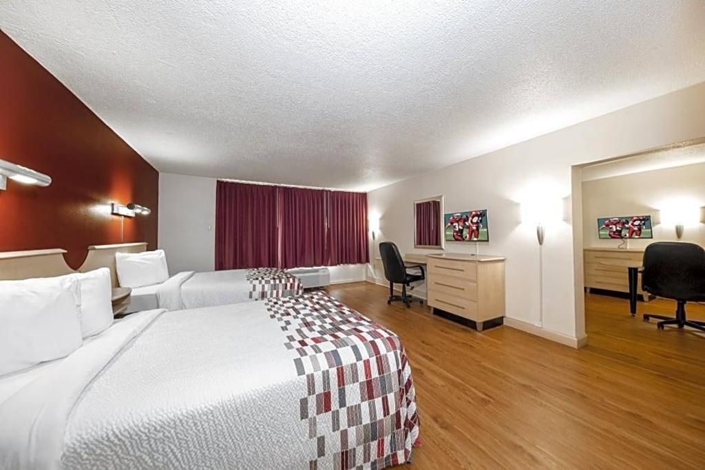 A hotel room with two beds, a desk, a chair, and a wardrobe.