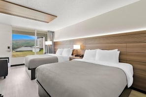 Ein Hotelzimmer mit zwei Betten, einem großen Fenster und Blick ins Freie.