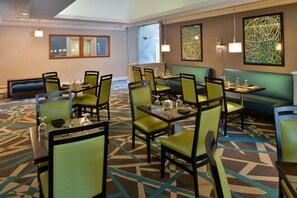 A hotel dining area with tables, chairs, and a patterned carpet. - Garden Plaza Hotel (Marietta)