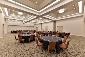 A large conference room with multiple round tables, chairs, and a patterned carpet. - Garden Plaza Hotel (Marietta)