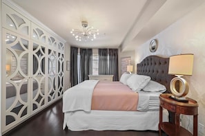 Une chambre à coucher comprenant un lit, une table de chevet, un miroir et un paravent décoratif.