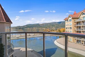 A building with a balcony overlooking a river and mountains. - Lakeview Townhouse in Sunset Waterfront Resort (Kelowna)