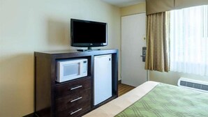 A hotel room with a bed, a TV on a dresser, a microwave, and a door. - Econo Lodge (Pittsfield)
