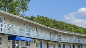 A motel with a row of rooms, a blue awning, and a balcony with railings. - Fairbridge Inn Express Pittsfield MA (Pittsfield)
