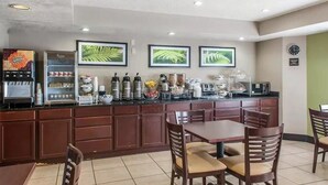 A kitchen area with a coffee machine, a microwave, and a refrigerator. There are framed pictures on the wall, a clock, and a dining table with chairs. - Rodeway Inn Airport Albuquerque, NM (Albuquerque)