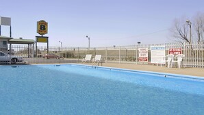 A swimming pool with a fenced area, lounge chairs, and a motel sign. - Super 8 Little Rock North Airport (North Little Rock)