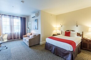 A hotel room with a large bed, a sofa, a desk, and a chair. - Artmore Hotel (Atlanta)