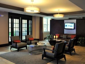 Un hall de hotel con zona de estar, un televisor y un ventanal grande.