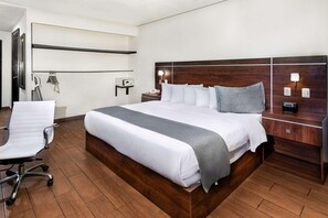 A hotel room with a large bed, a desk, a chair, and a bedside table with a lamp. - Tru by Hilton Saltillo (Saltillo)